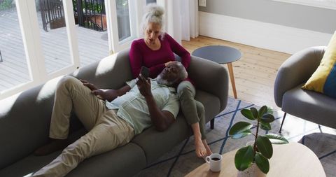 Senior Couple Relaxing on Couch with Smartphone at Home