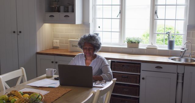 Senior woman working remotely on laptop in cozy kitchen - Download Free Stock Images Pikwizard.com