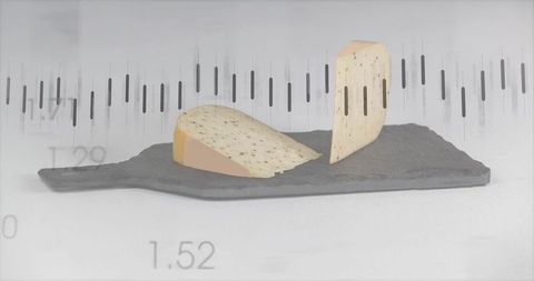Herbed cheese wedges on dark slate with minimalist numeric waveform overlay and studio lighting