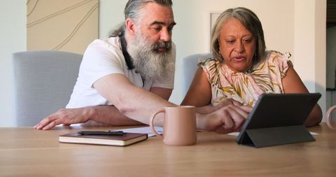 Senior Couple Using Tablet for Online Browsing at Home