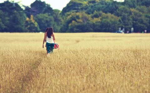 Woman Walking Through Golden Field in Tranquil Setting