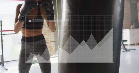 Female boxer punching heavy bag in bright loft gym with data grid overlay