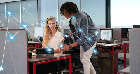 Coworkers collaborating on tablet in open-plan office with digital network and analytics