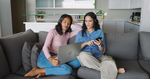 Diverse Women Collaborating with Laptop and Smartphone in Modern Living Room