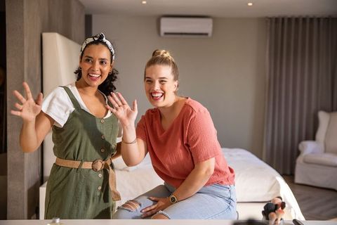 Cheerful female friends waving in modern cozy bedroom