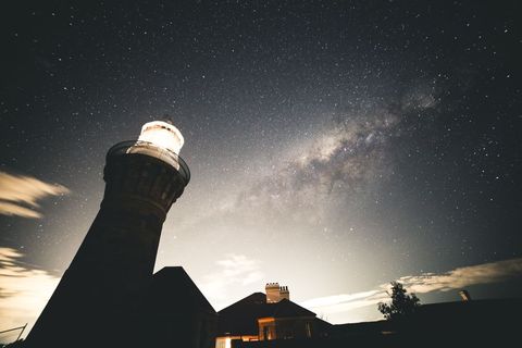 Majestic lighthouse under starry night sky with milky way