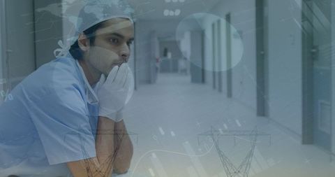 Tired doctor sitting in hospital corridor with financial graph overlays