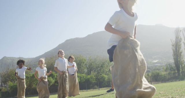 Diverse children enjoy a sunny day with a friendly sack race, promoting fun and fitness. - Download Free Stock Photos Pikwizard.com