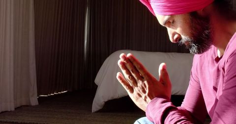 Man meditating peacefully in sunlit room with hands together