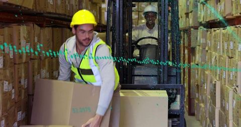 Warehouse Worker Lifting Box with Forklift in Background