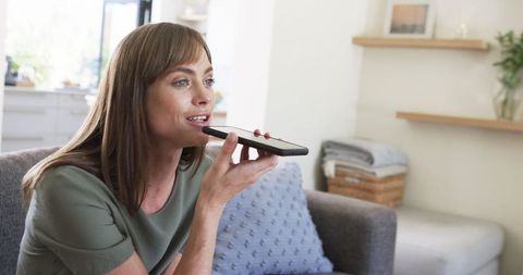 Woman Using Smartphone for Voice Message in Bright Living Room