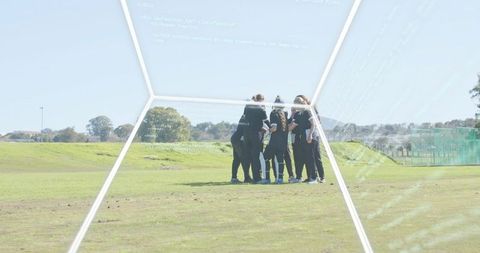 Female team huddling on grass pitch during outdoor practice — strategy talk and coaching