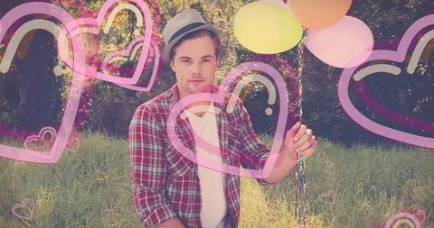 Man holding pastel balloons in meadow with pink heart overlay