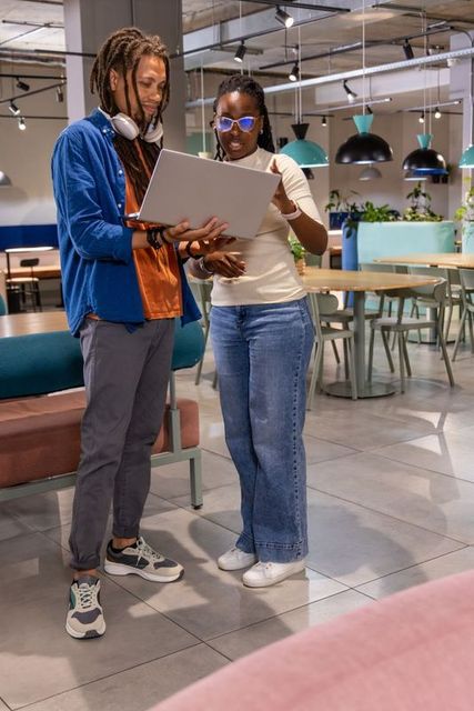 African american colleagues collaborating over laptop in modern coworking lounge