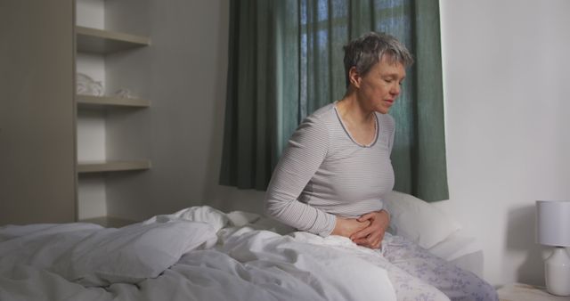 Senior Woman Experiencing Stomach Pain Sitting on Bed - Download Free Stock Images Pikwizard.com