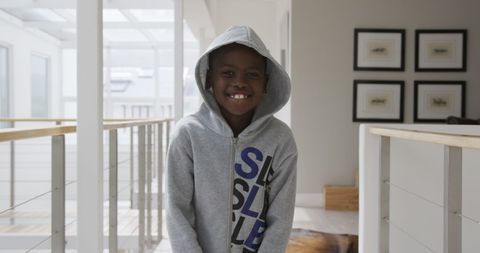Cheerful african american boy in gray hoodie laughing indoors