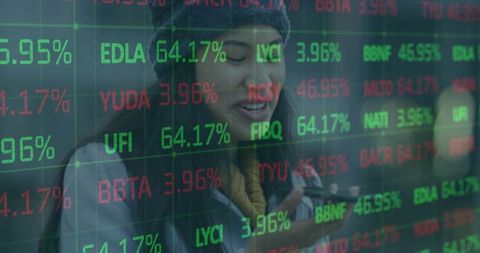 Woman holding smartphone viewing stock market ticker reflected on glass storefront window
