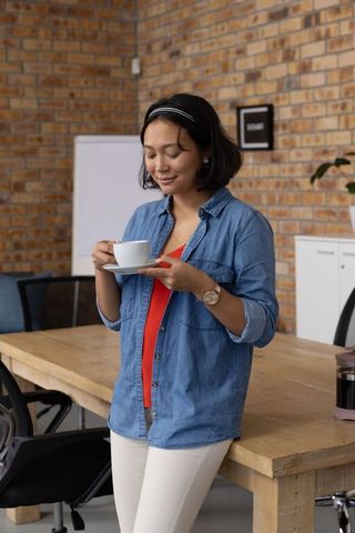 Young Woman Enjoying Coffee Break in Loft Style Workspace