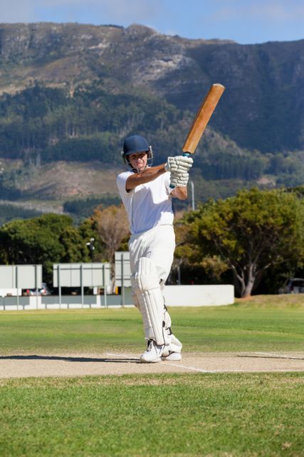 Cricketer batting on sunny day with scenic mountain backdrop - Download Free Stock Photos Pikwizard.com