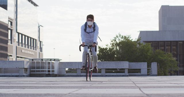 Man is biking in an urban area while wearing a face mask, emphasizing health and transportation in the city. This can be used in content related to urban commuting, health measures, sustainable transportation, and daily exercise routines.