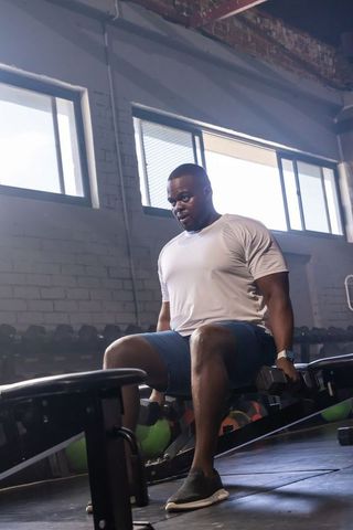 African american man lifting dumbbells on bench in urban gym focused strength training