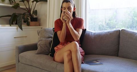 Woman Relaxing with Coffee on Comfortable Gray Sofa in Modern Living Room
