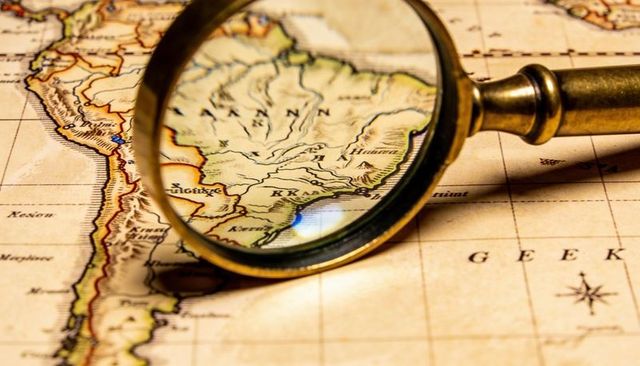 Vintage brass magnifier enlarging south america map on parchment with compass rose
