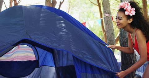 Woman setting up tent for camping adventure outdoors