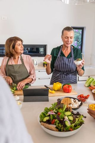 Senior Women Preparing Salad Together in Modern Kitchen