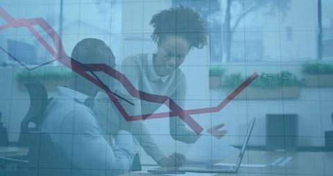 Business colleagues collaborating over laptop with financial chart overlay in office