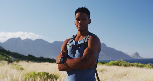Portrait of african american man cross country running in mountain countryside looking at the camera and smiling. fitness training and healthy outdoor lifestyle.