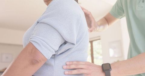 Caregiver supporting senior woman in blue sweater at home providing eldercare and comfort