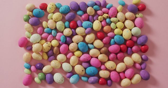 Vibrant assortment of mini chocolate eggs in various colors displayed on pink backdrop. Ideal for Easter-themed designs, holiday banners, invitations, and festive advertisements. Perfect for adding a cheerful and colorful touch to any spring or celebration-related project.