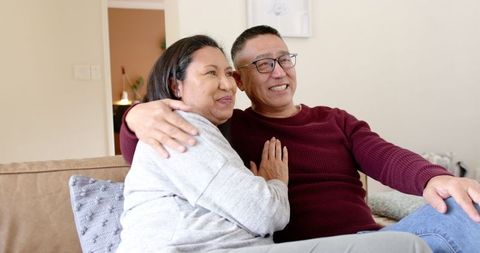 Senior Couple Embracing on Beige Sofa in Cozy Living Room