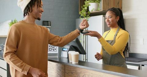 Contactless cafe payment: african american customer tapping smartwatch at coffee counter