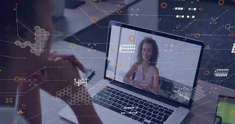 Woman video calling on laptop during virtual meeting with digital HUD overlay