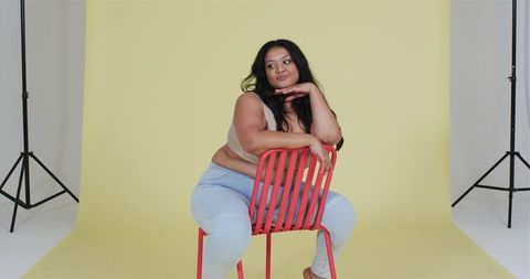 Confident Woman Seated on Red Chair in Creative Studio Setting