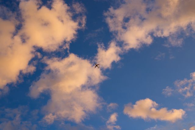 Airplane soaring high among colorful clouds at sunset, representing travel, freedom, and adventure. Perfect for use in travel brochures, aviation advertisements, motivational posters, and social media content about wanderlust.