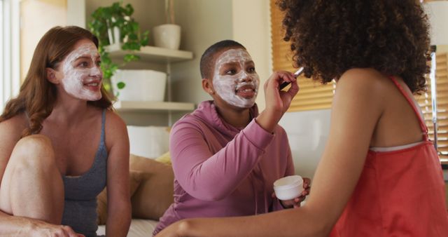 This photo shows diverse women enjoying a home spa day, applying facial masks and bonding. Perfect for blogs or articles about self-care, wellness, and friendship, or for marketing skincare and beauty products.
