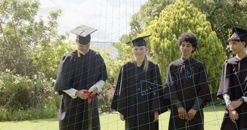 Graduates wearing cap and gown celebrating diplomas on campus lawn