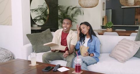 Casual Couple Enjoying Takeout at Home on Comfortable Sofa