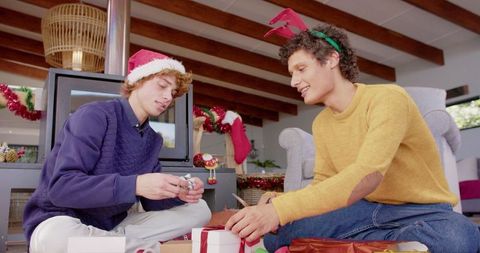 Diverse gay male couple wrapping christmas presents at home