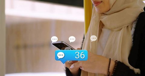 Young woman wearing hijab texting on smartphone with 36 chat notifications on public transit