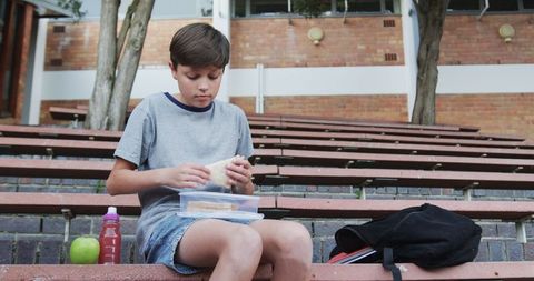 Young boy enjoys lunch outdoors at school campus