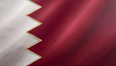Qatar flag displaying maroon and white serrated band with gold trim and textile texture