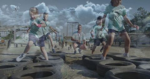 Energetic children running tire obstacle course with coach