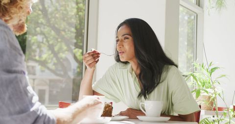 Happy Interracial Couple Enjoying Cake in Bright Cafe