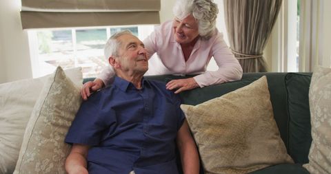 Elderly Couple Sharing Joyful Moment on Couch in Daylight