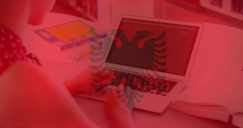 Albania Flag Overlaying Businesswoman on Laptop Demonstrating Patriotism