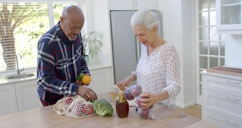 Senior Interracial Couple Unpacking Groceries in Modern Kitchen